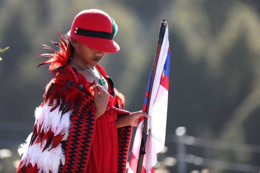 A young person in traditional dress holds a flag.