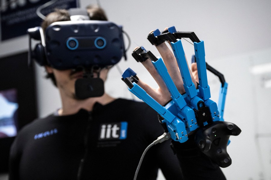 A person poses while wearing VR goggles and glove controllers.