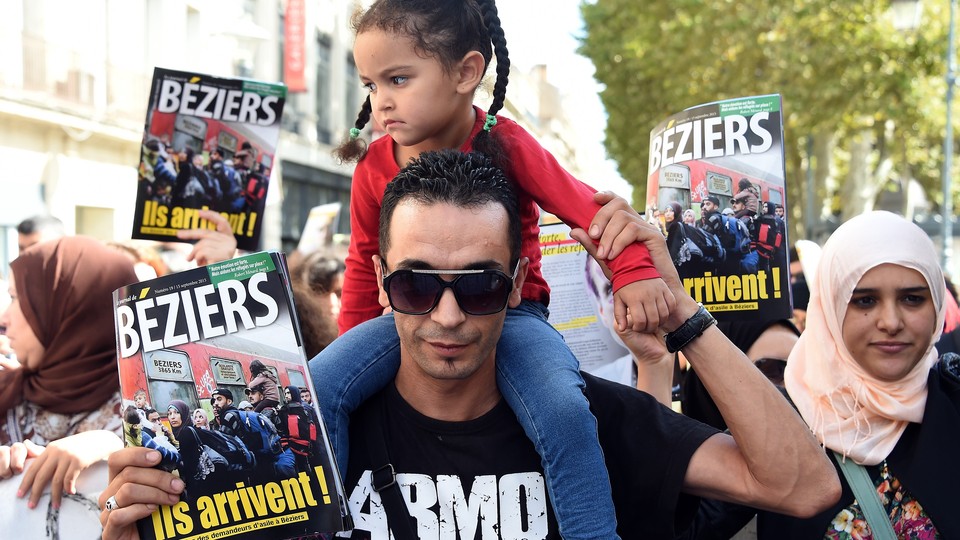 People take part in a demonstration to protest against the mayor of the French city of Beziers and to support Syrian refugees.