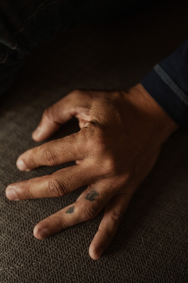 a man's left hand, with two tattoos on his ring finger