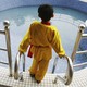 A young boy looks out at a big pool