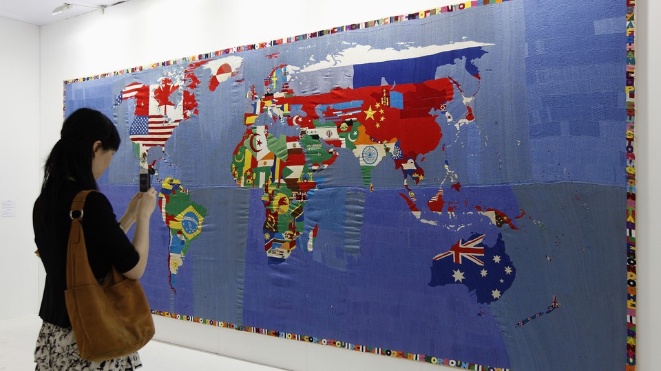 A woman takes a photo of a map. The countries' flags fill their borders in the representation.