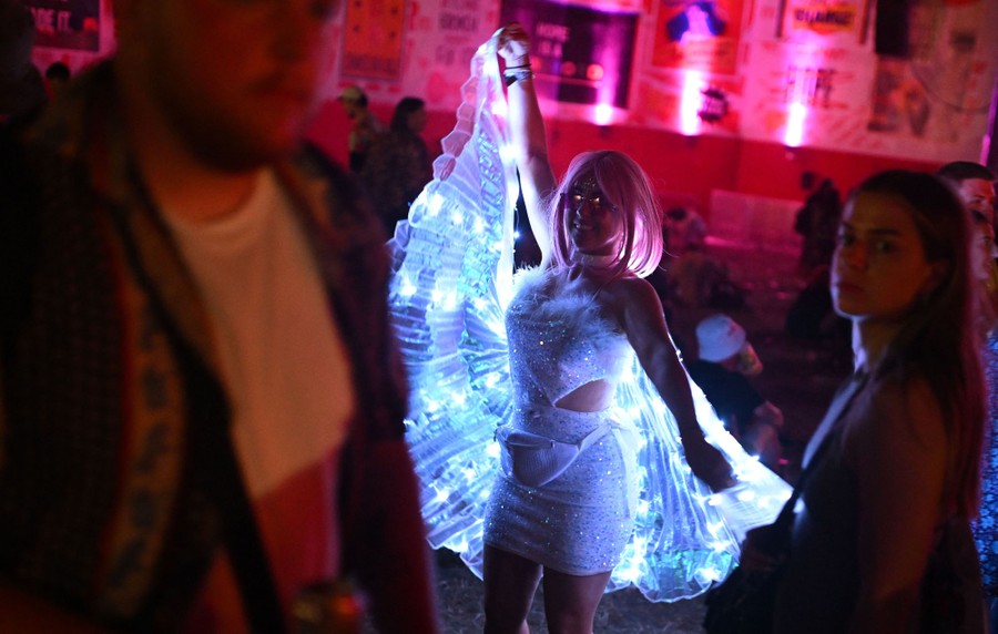 A concertgoer dances while wearing an illuminated cape.