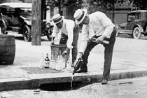 Two men pour liquor down a storm drain during the Prohibition era