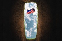 An American flag is viewed against the sky, from inside a freshly dug grave