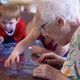 An elderly woman does a puzzle with children