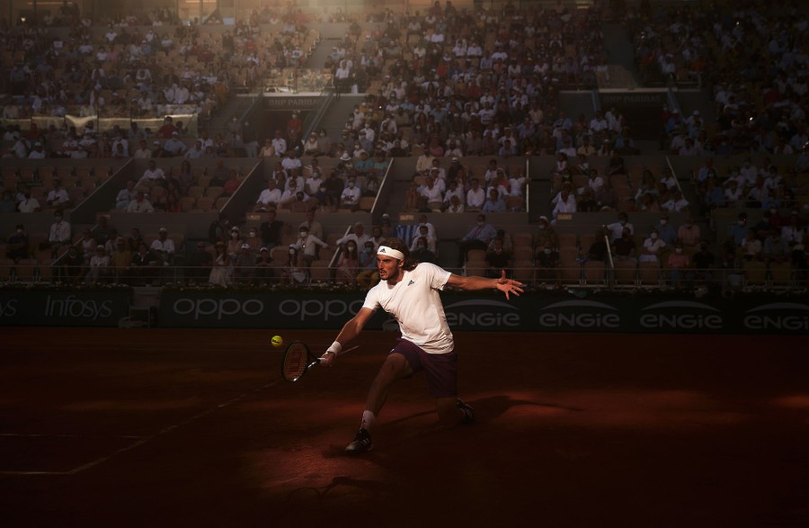 A tennis player hits a backhand as a large crowd watches from the stands.
