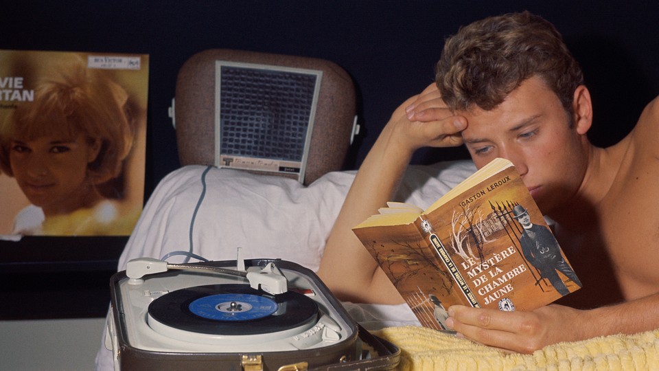 A young man reads a book at night.