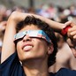 A person stares up with eclipse glasses on, their lips curled back