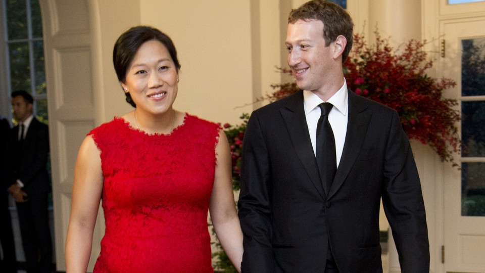 Mark Zuckerberg and Priscilla Chan walk while holding hands and wearing formalwear.