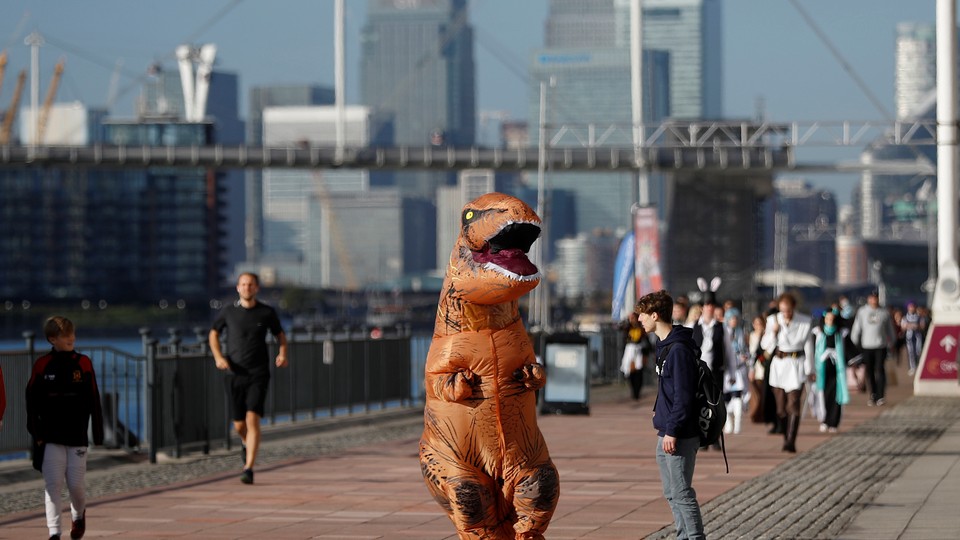 A person in a T-rex costume on a riverside walking path in London