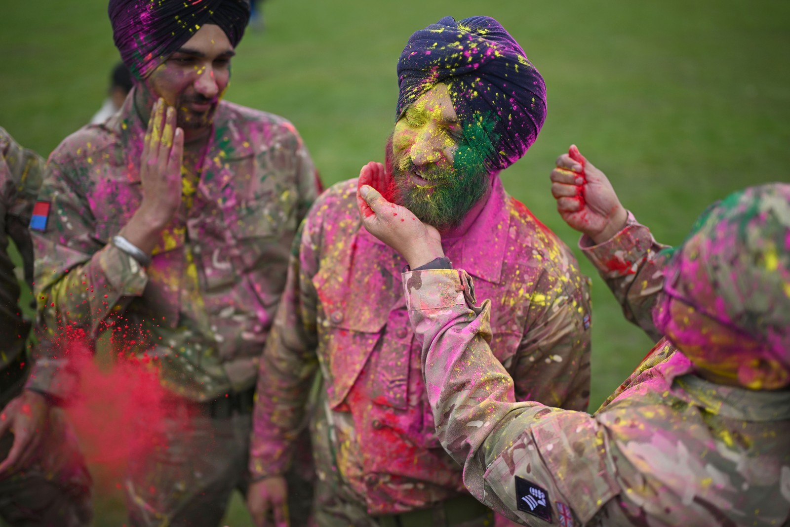 Sikh soldiers cover each other with colored powder during a festival.