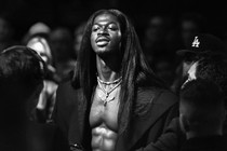 black-and-white photo of shirtless Lil Nas X wearing a black coat