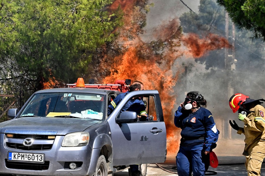 Several firefighters near a small truck move away from an approaching fire.
