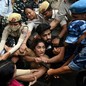 Police officers struggle to pull protesters away from each other.