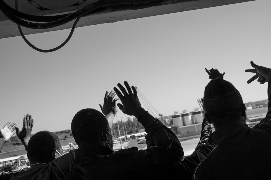 Migrants waving from onboard a ship