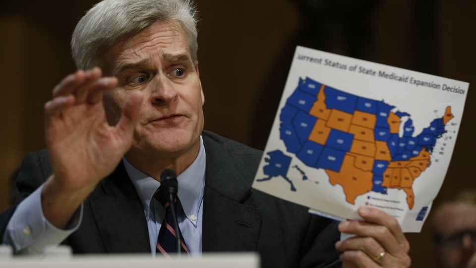 Senator Bill Cassidy of Louisiana holds a map of projected federal spending on health care, by state.