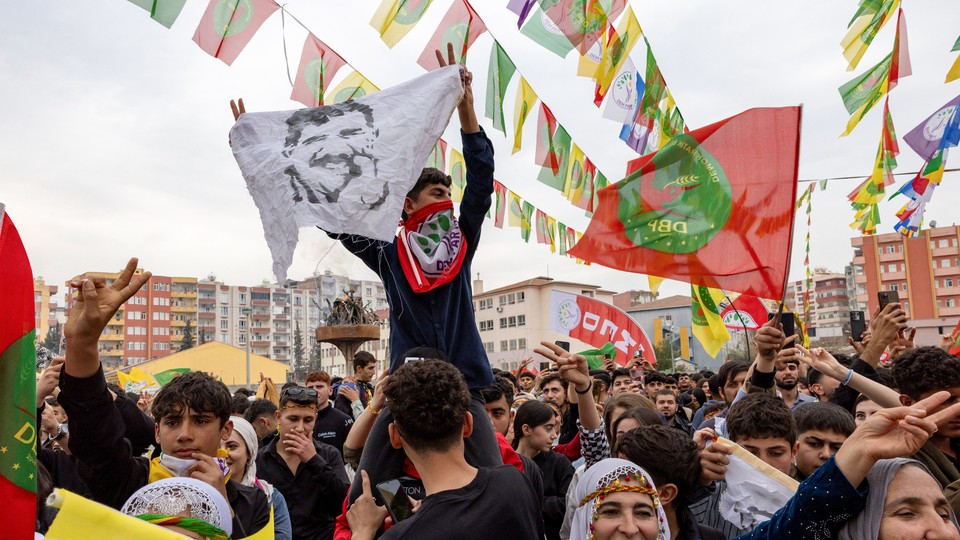 A man holds up a flag of a jailed Kurdish leader at a festival