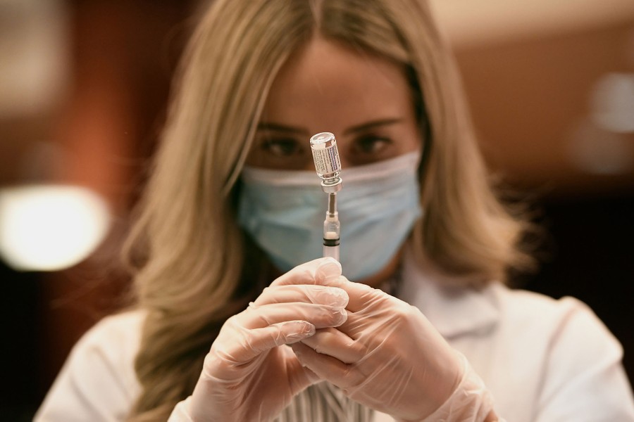 A person draws a dose of vaccine into a syringe.