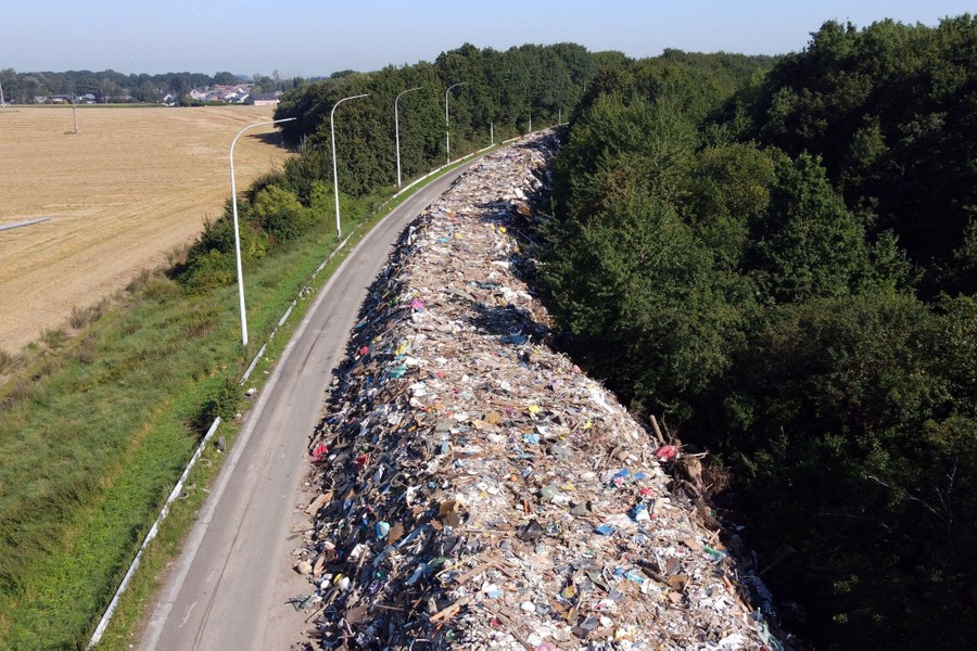 A long pile of garbage and wreckage snakes along an abandoned highway.
