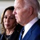 Photograph of Joe Biden, slightly blurred in the foreground, and Kamala Harris in focus in the background looking at Biden.