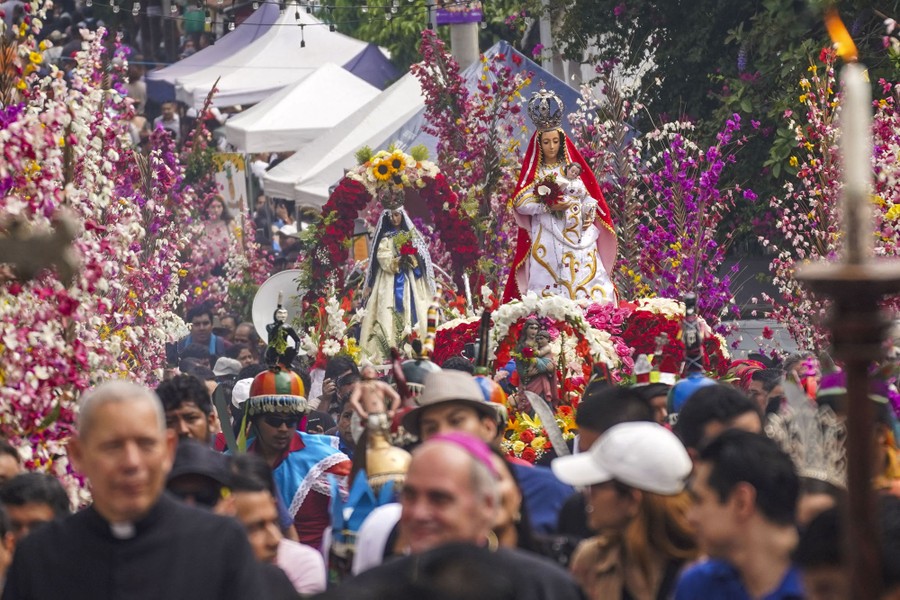 People carry statues of the Virgin Mary in a flower-strewn procession.