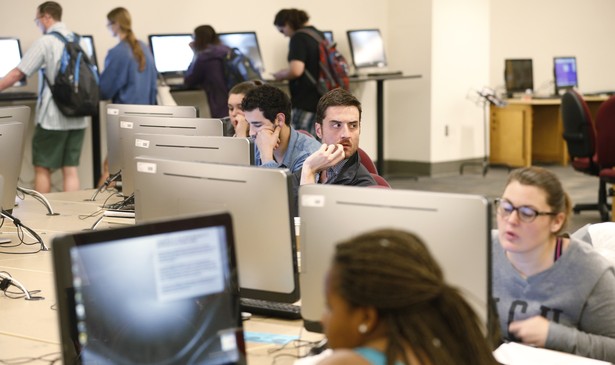 A row of people sitting at computers in a library