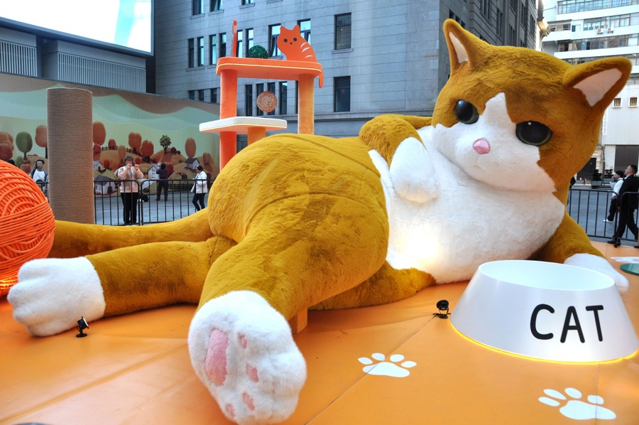 A giant installation depicting a resting cat sits in a public square.
