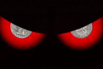 An illustration showing a pair of evil-looking eyes with coins for pupils