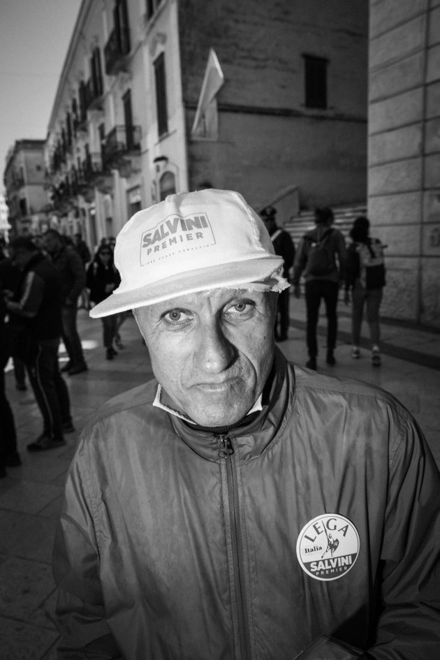 A man wearing a baseball cap and button in support of Matteo Salvini.