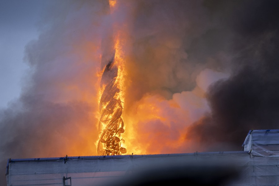 A steep, twisting tower above a building burns.