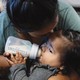 Photograph of a young child drinking from a bottle
