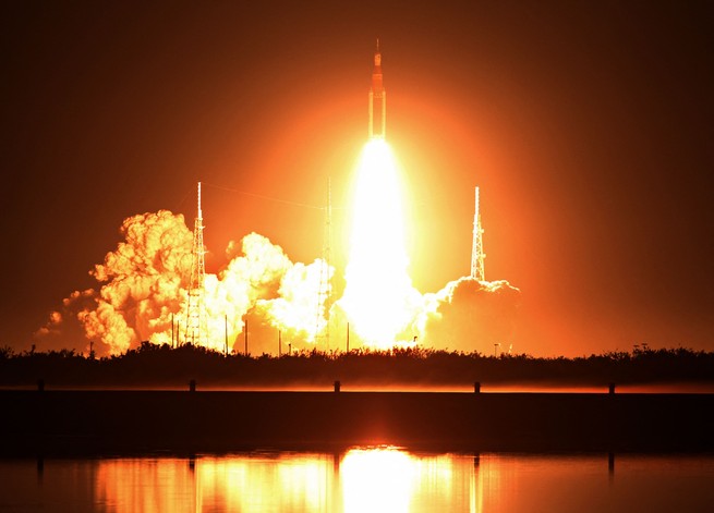 NASA's new moon rocket, the Space Launch System, lifts off from the launchpad, its engines blazing bright