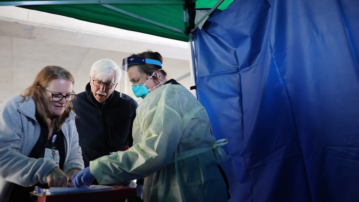 Carroll Hospital Critical Care Unit workers organize samples taken from people being tested for the coronavirus at a drive-through station in the hospital's parking garage