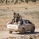 Syrian Democratic Forces fighters ride a pickup truck with Islamic State fighters held as prisoners.