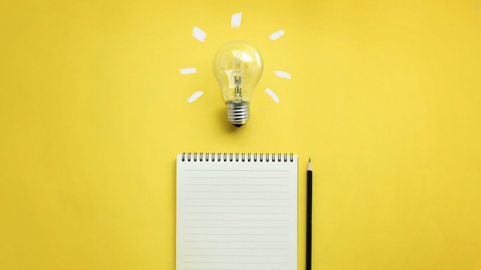 lightbulb, lined notepad, and pencil on yellow background