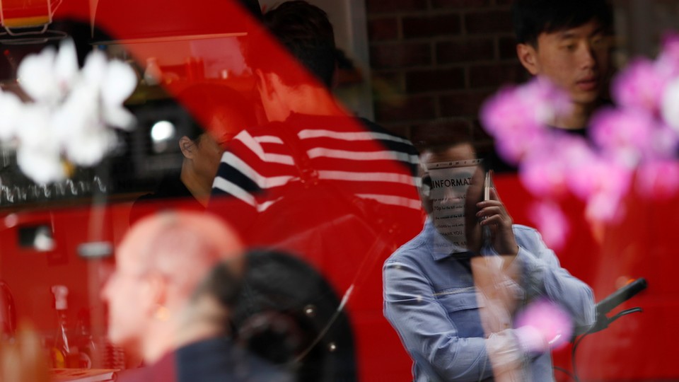 A man is reflected in a window as he uses his mobile phone