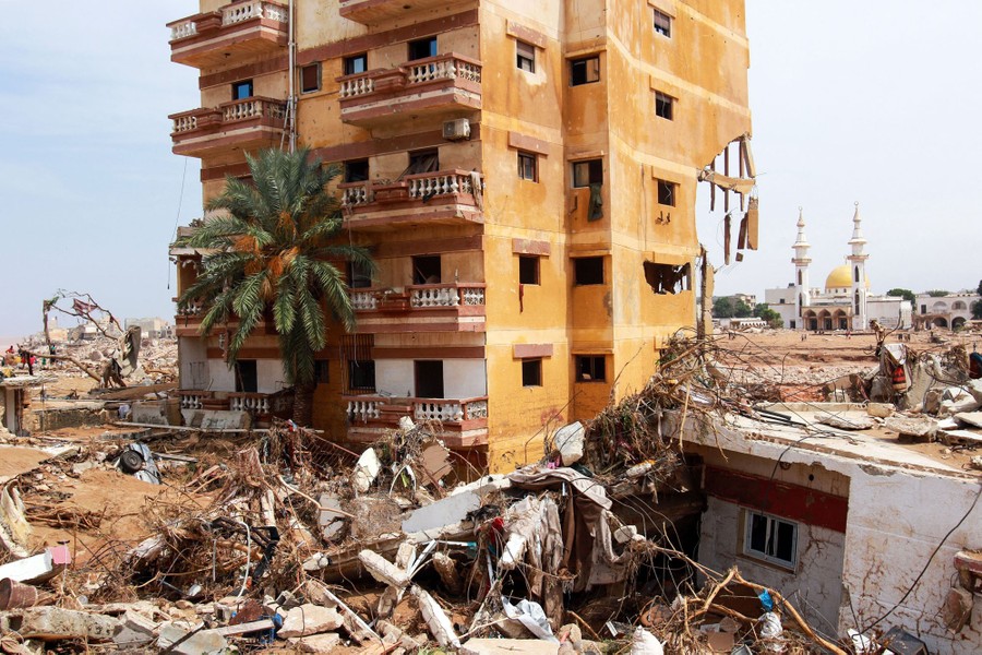 Piles of flood debris sit alongside damaged residential buildings.