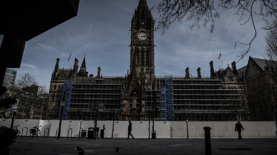 A man walks in front of Manche​ster Town Hall in the deserted​ center of Manchester after Prime Minister Boris Johnson​ imposed a lockdown on England.