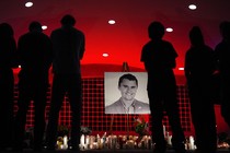 Silhouettes of people looking at a photo of Charlie Kirk at a vigil for him in Utah.
