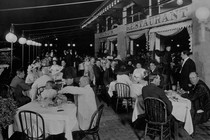 A black-and-white photo of people dining outside