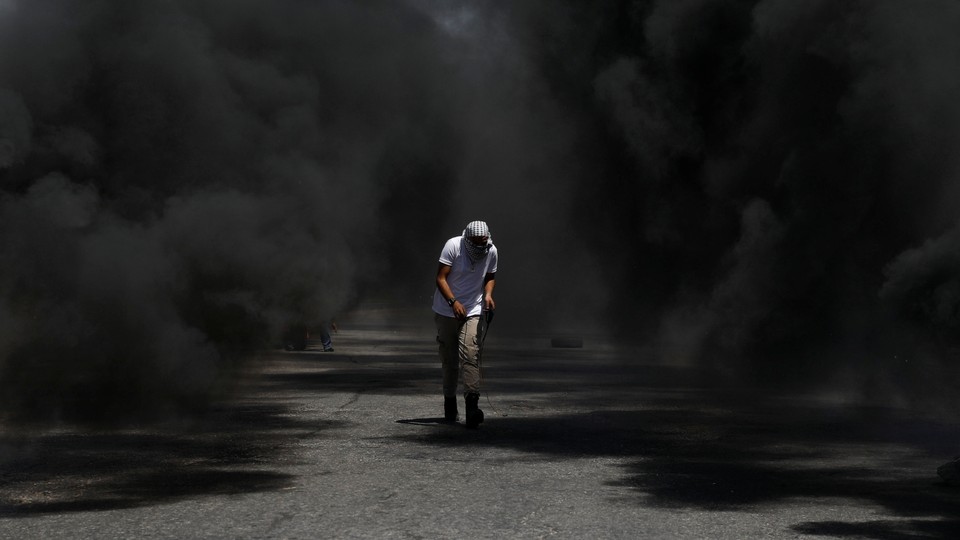 A protester crouching in black smoke
