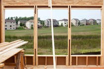 A suburban neighborhood captured through the window of a house in construction