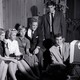 A black-and-white photograph from the 1950s showing teens watching TV in a living room