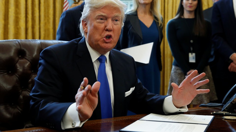 President Trump holds up a signed memo pulling the U.S. out of the TPP