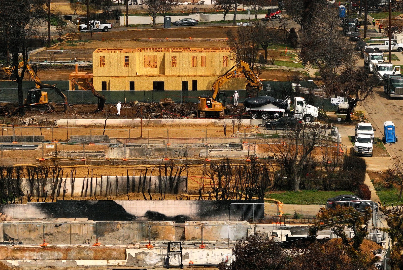 Workers clear a lot next to a new home under construction.