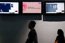 Photo of airline passengers passing a monkeypox virus information screen