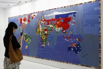 A woman takes a photo of a map. The countries' flags fill their borders in the representation.