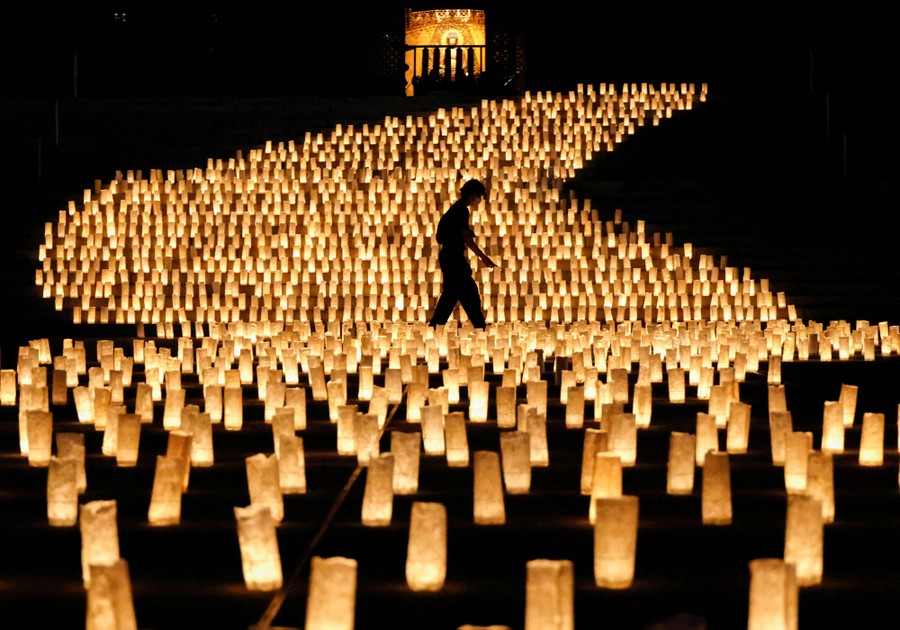 A person walks in front of a large display of paper lanterns.