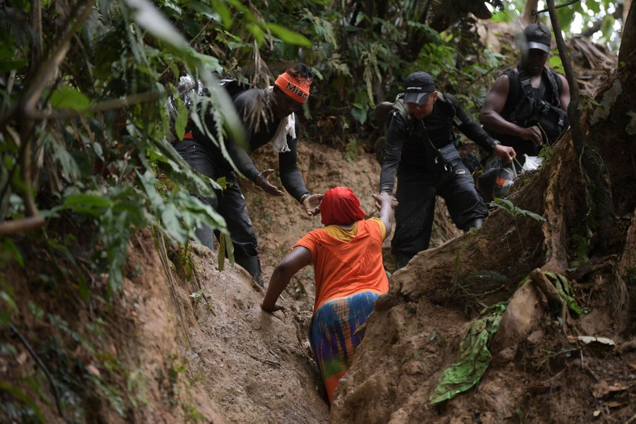People climb a steep muddy path.